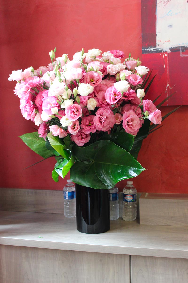 d’un vase noir garni d’un bouquet de lisianthus rose